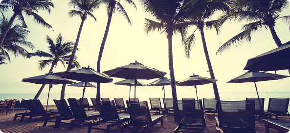 Beach scene with palm trees, umbrellas and lounge chairs
